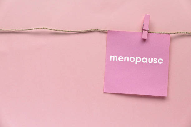 Pink paper hanging on the rope written with menopause on a pink background.